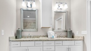 A bathroom with two mirrors, a granite countertop, and white cabinetry. - Driftwood Townhomes #8 (Miramar Beach)