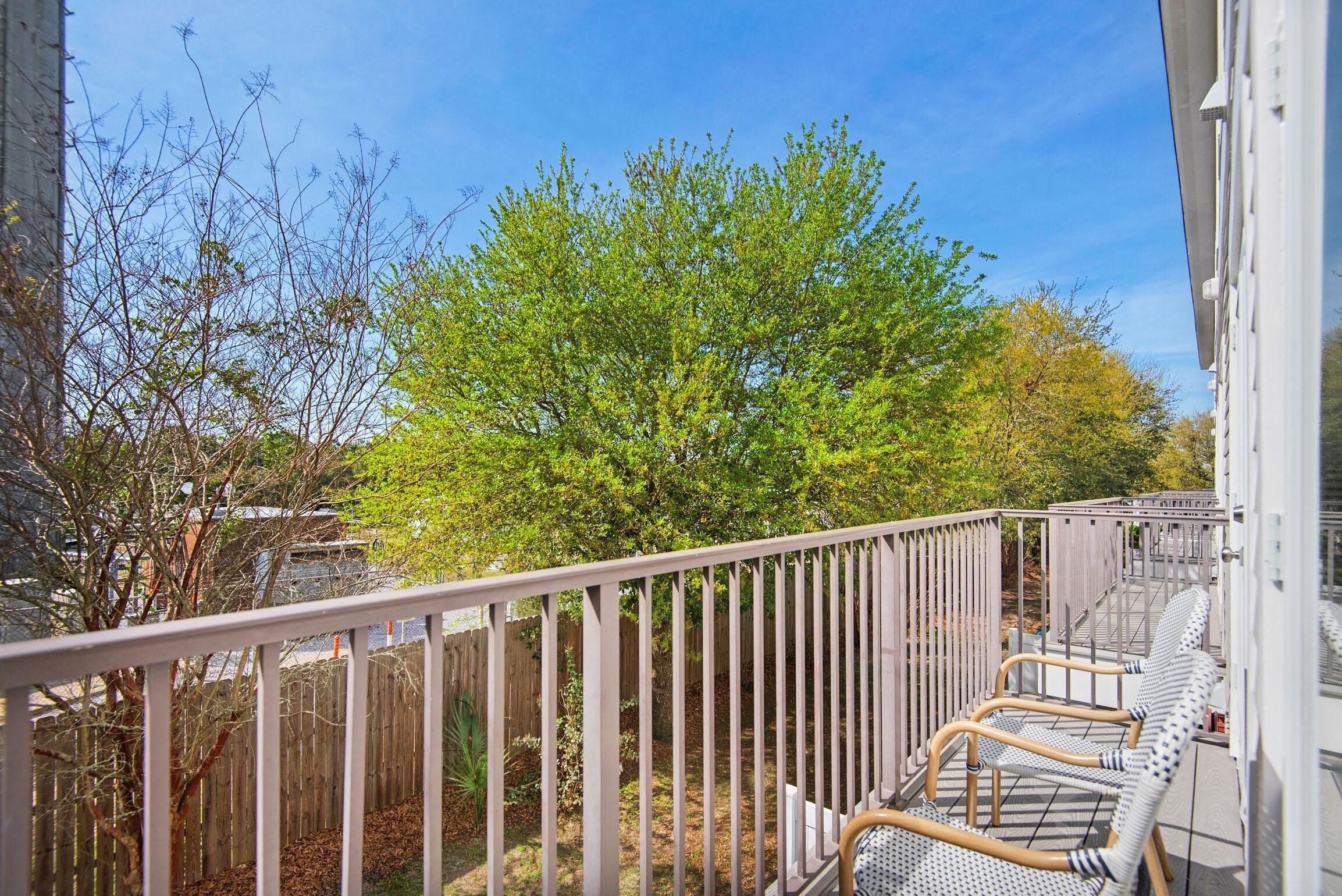 A balcony with a view of a tree and a fence.
