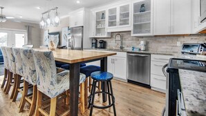 A modern kitchen with white cabinets, a stainless steel refrigerator, a coffee maker, and a toaster. - Driftwood Townhomes #8 (Miramar Beach)