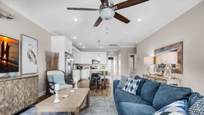 A modern living room with a blue sofa, a wooden coffee table, and a ceiling fan. - Driftwood Townhomes #8 (Miramar Beach)