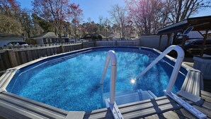 A swimming pool with a wooden deck and a metal ladder.