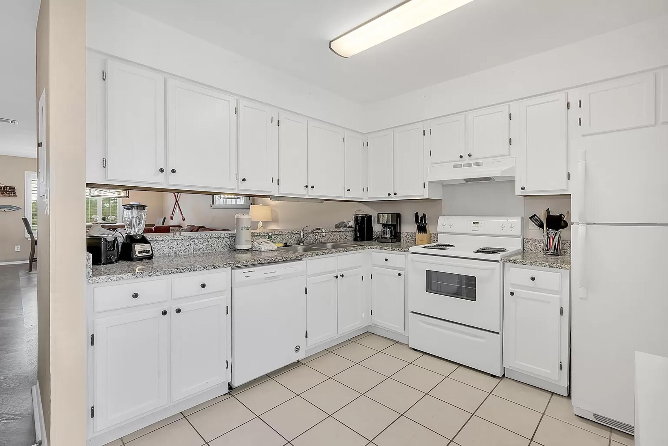 A modern kitchen with white cabinets, a granite countertop, and stainless steel appliances including a stove, oven, and refrigerator.