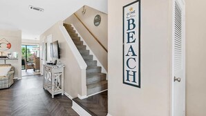 Una escalera conduce a un segundo piso, con un cartel en la pared que dice "BEACH".