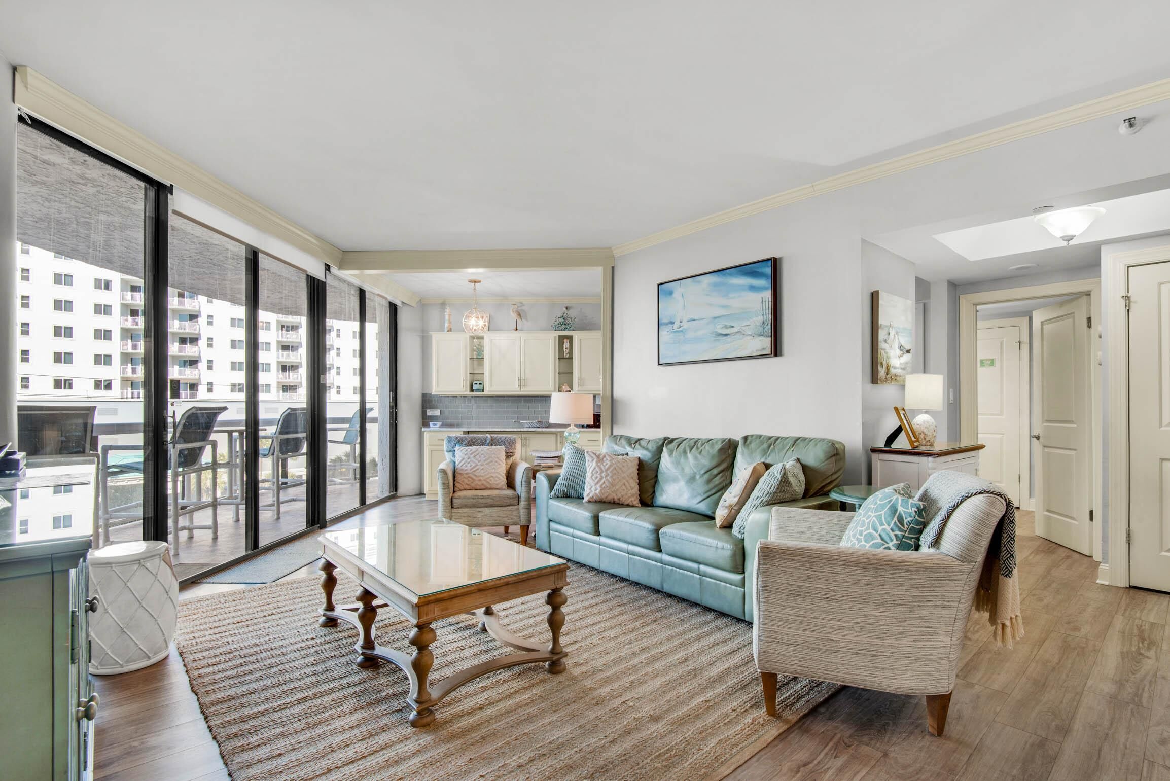 A spacious living room with a large window, a sofa, a coffee table, and a dining area.