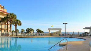 A swimming pool with a clear view of the ocean, surrounded by palm trees and a covered area with chairs. - Captiva 67 (Miramar Beach)