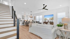 A spacious living area with a sofa, dining table, and kitchen in the background. - Keeping It Reel on 30A (Santa Rosa Beach)