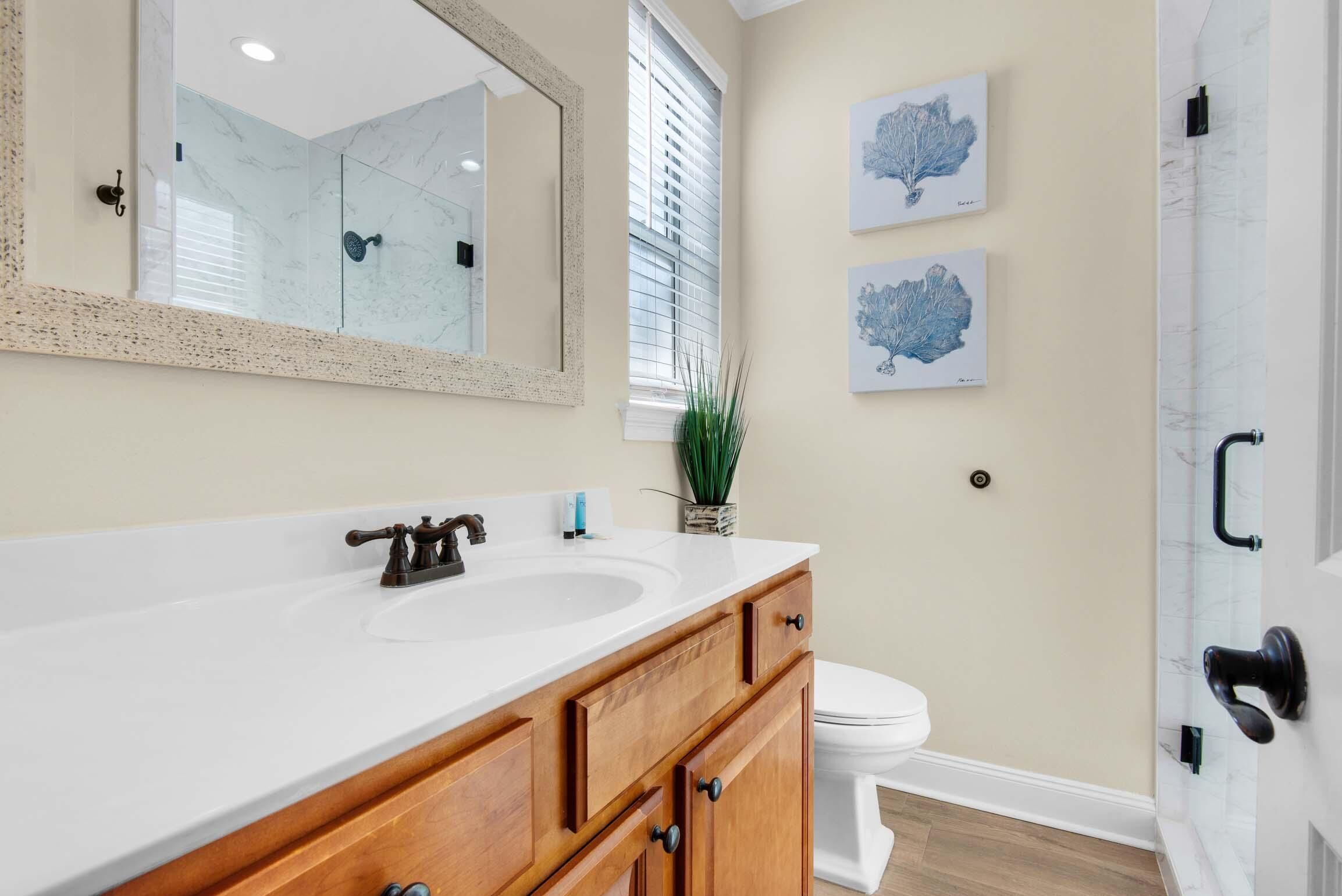 A bathroom with a white sink, wooden vanity, a large mirror, and two wall-mounted artwork pieces.