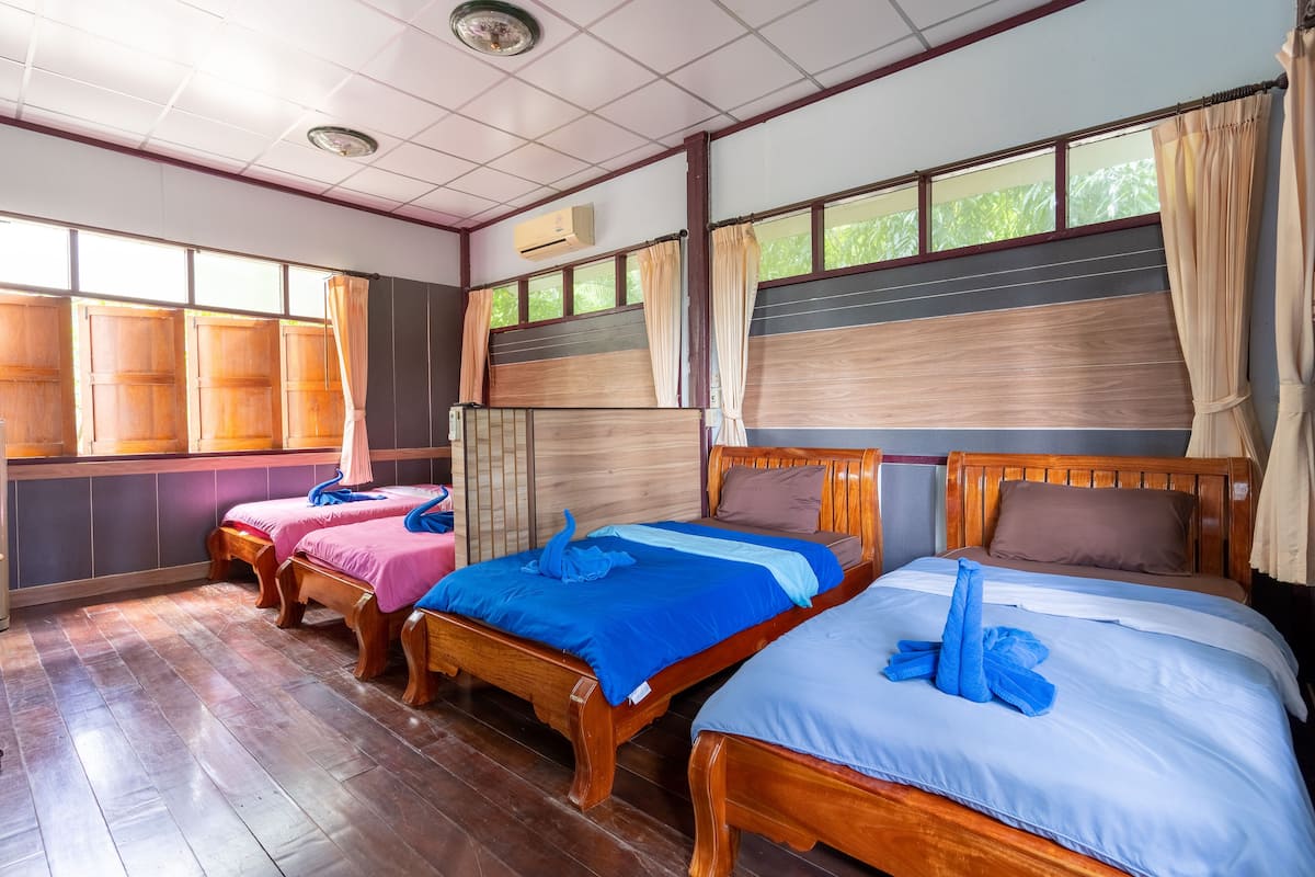 A hotel room with three wooden beds, each with blue and white bedding.