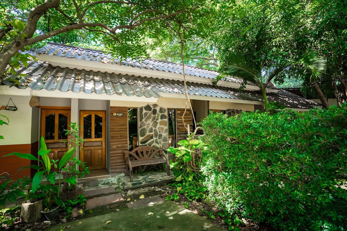 A traditional house with a tiled roof, wooden doors, and a stone wall entrance.