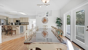 Una cocina amplia con una isla grande, sillas de madera y una mesa de comedor con un reloj.