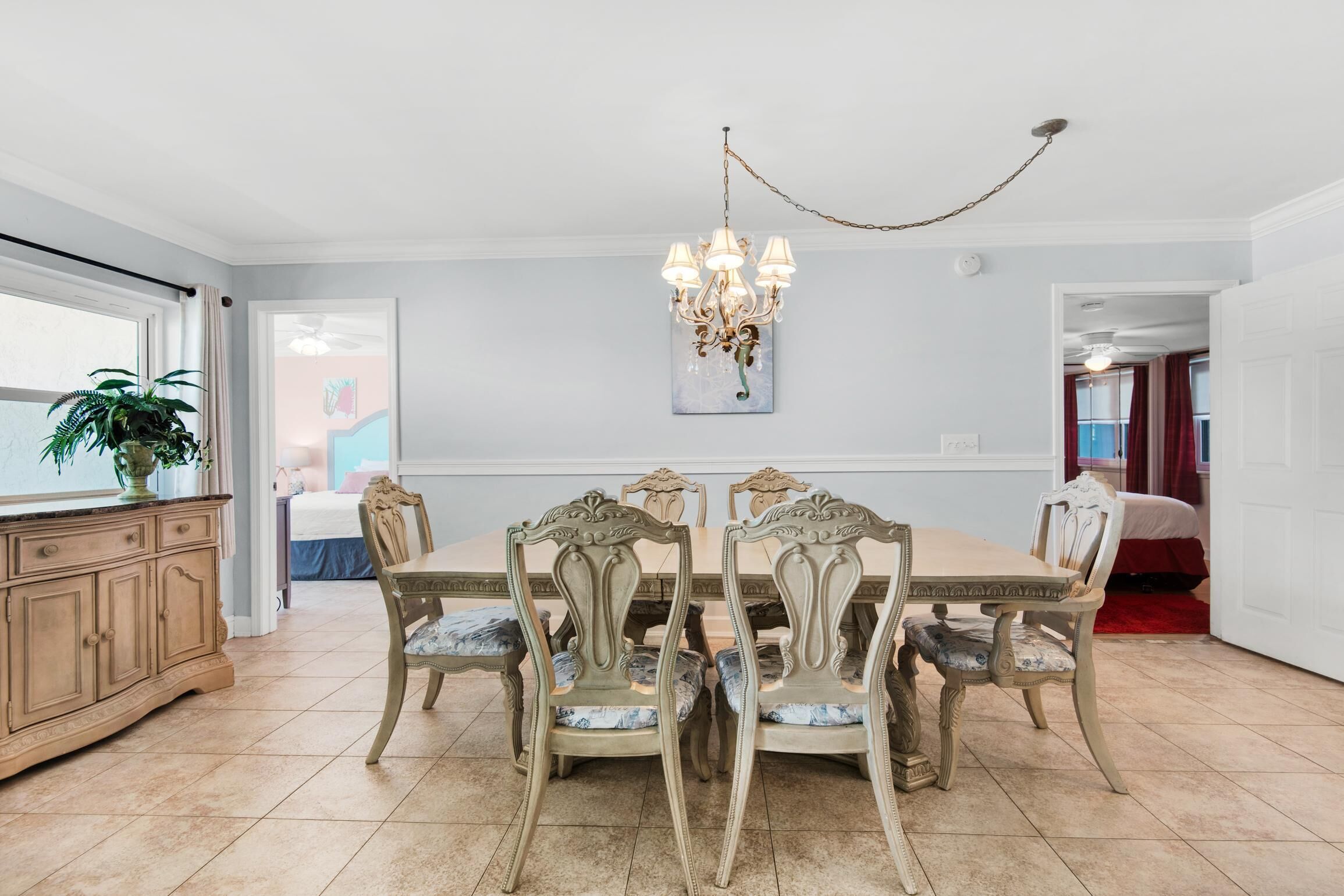 A dining room with a chandelier, a large table, and six chairs.