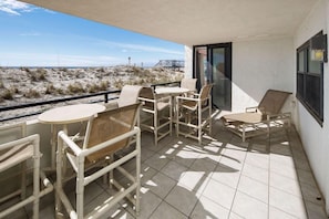 Un balcone con vista sulla spiaggia, dotato di tavolo e sedie.