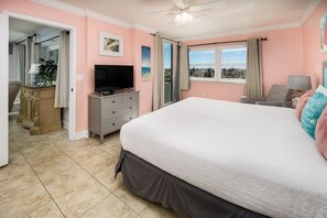 A bedroom with a large bed, a television, a desk, and a view of the outside. - Nautilus 1102 (Fort Walton Beach)