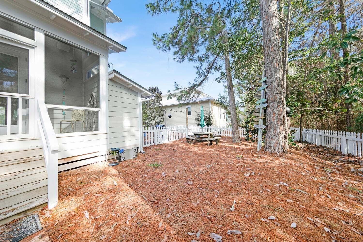 A residential property with a covered porch, a fenced backyard, and a picnic table.