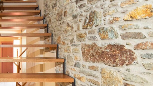 Un escalier avec des marches en bois et un mur en pierre.