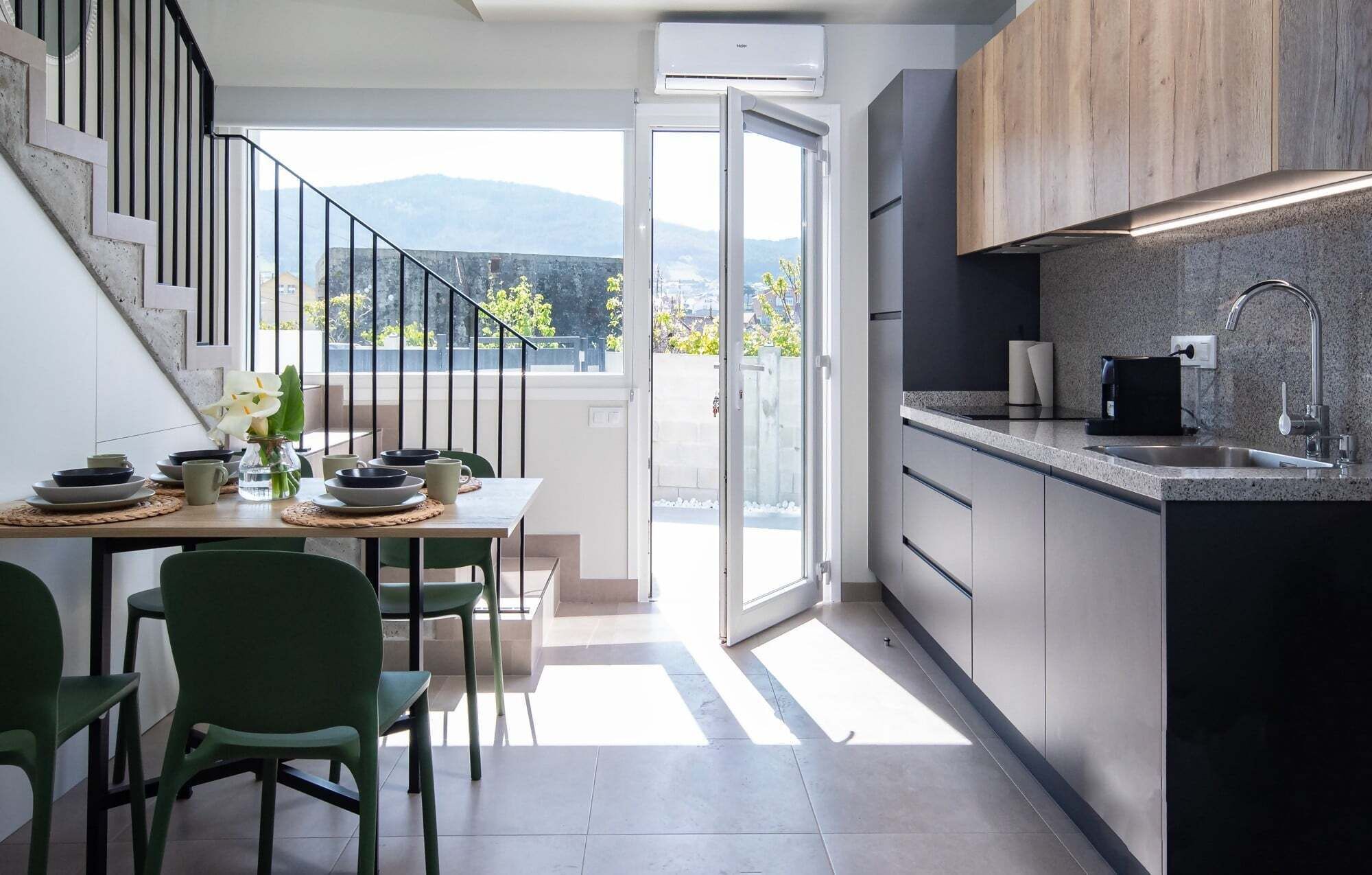Una cocina moderna con estufa integrada, un fregadero y vistas a montañas a través de un ventanal.