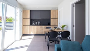 Una cocina moderna con armarios de madera, encimera negra y un comedor con mesa y sillas.