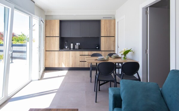 A modern kitchen with wooden cabinets, a black countertop, and a dining area with a table and chairs.