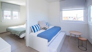 Un dormitorio con una cama, una mesita y una ventana.