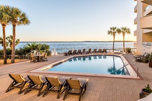 A pool area with lounge chairs and a table, overlooking the sea. - East Pass 403 (Destin)