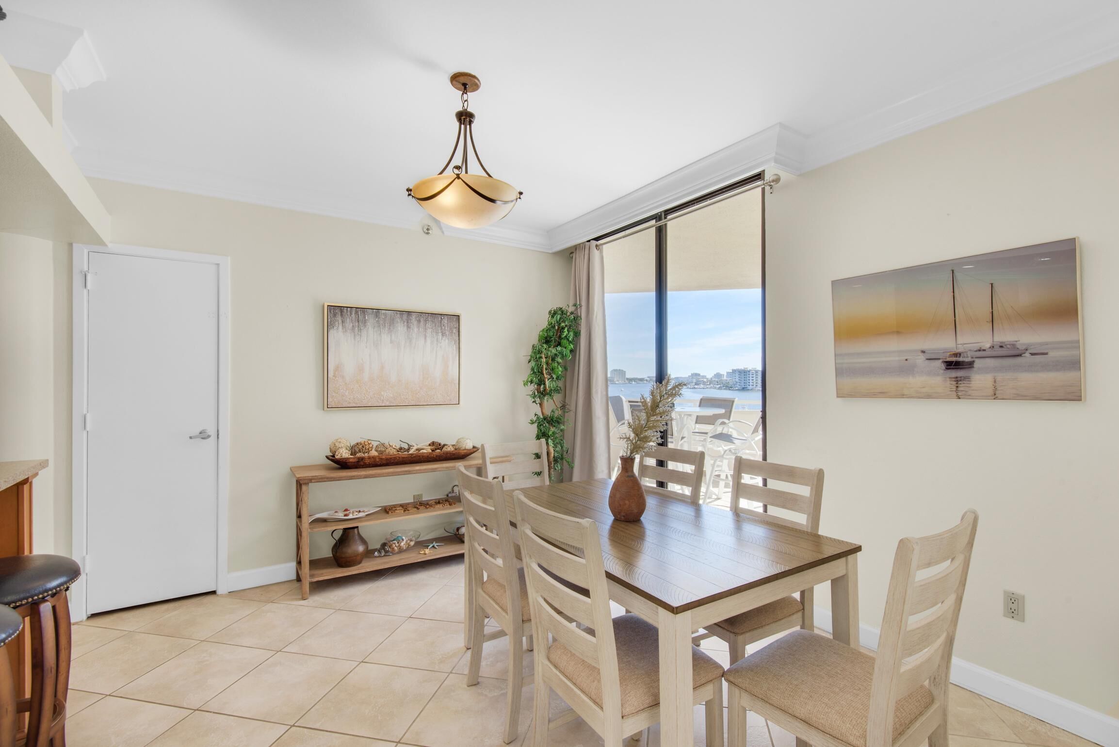 Un coin repas avec une table et des chaises, un luminaire suspendu, une plante et un tableau au mur.
