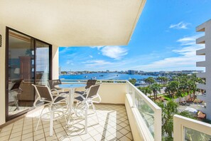 A balcony with a table and chairs, overlooking a marina with boats and a cityscape. - East Pass 403 (Destin)