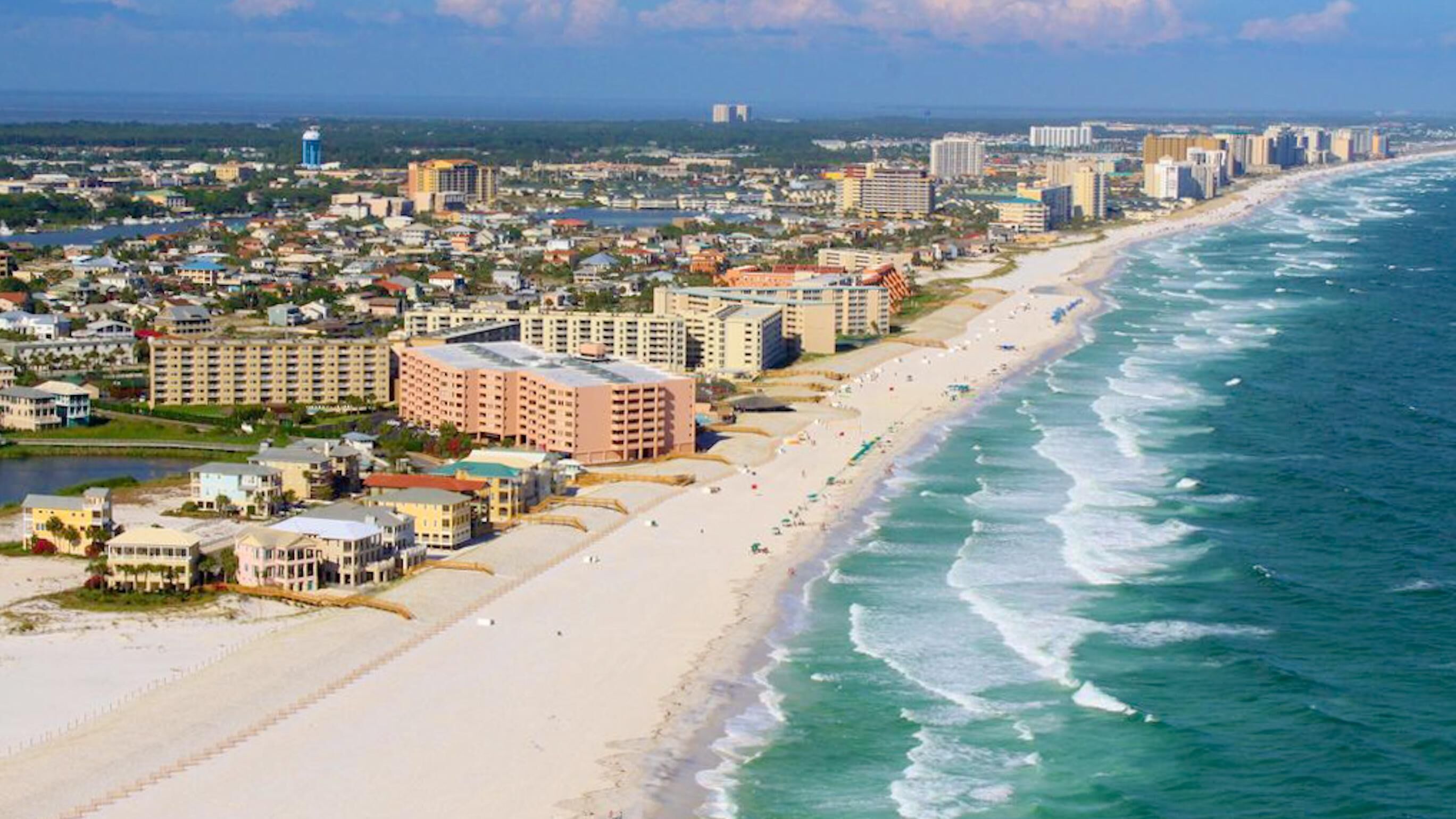 A coastal cityscape with beachfront hotels, a sandy beach, and ocean views.