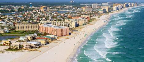 A coastal cityscape with beachfront hotels, a sandy beach, and ocean views.