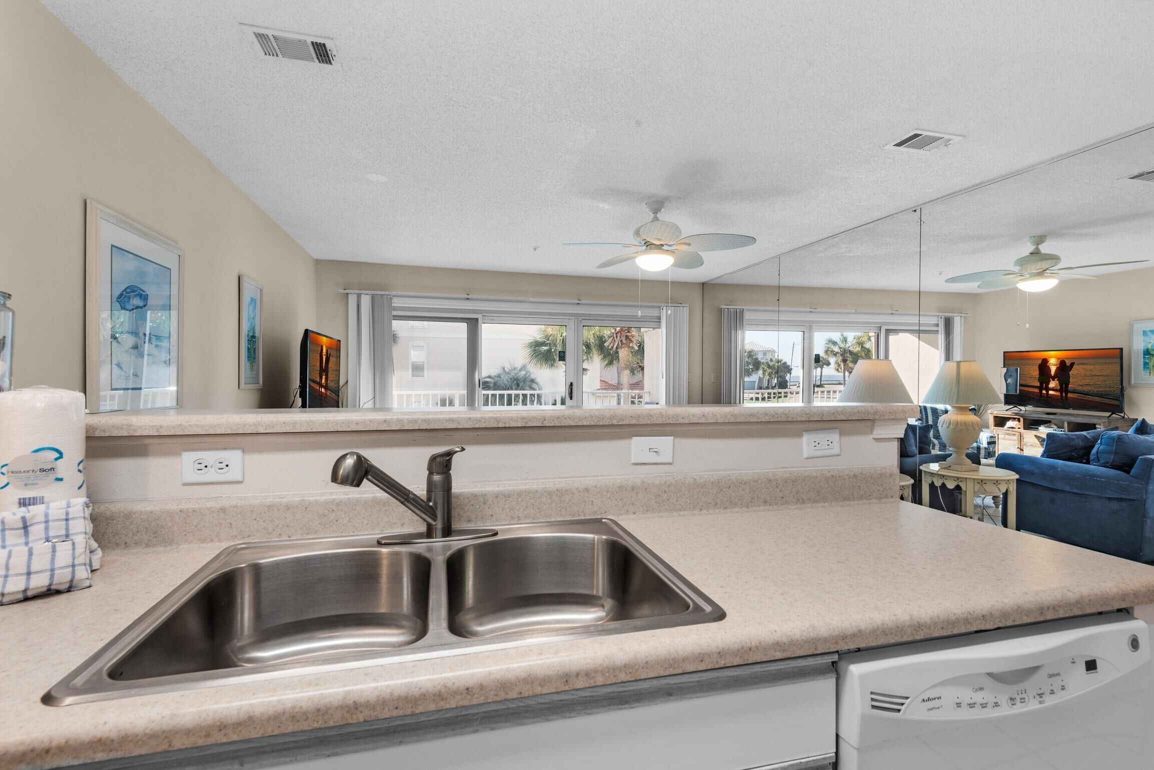 A modern kitchen with a double sink, a dishwasher, and a large window overlooking a balcony.