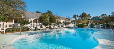 A swimming pool with lounge chairs and a white picket fence.