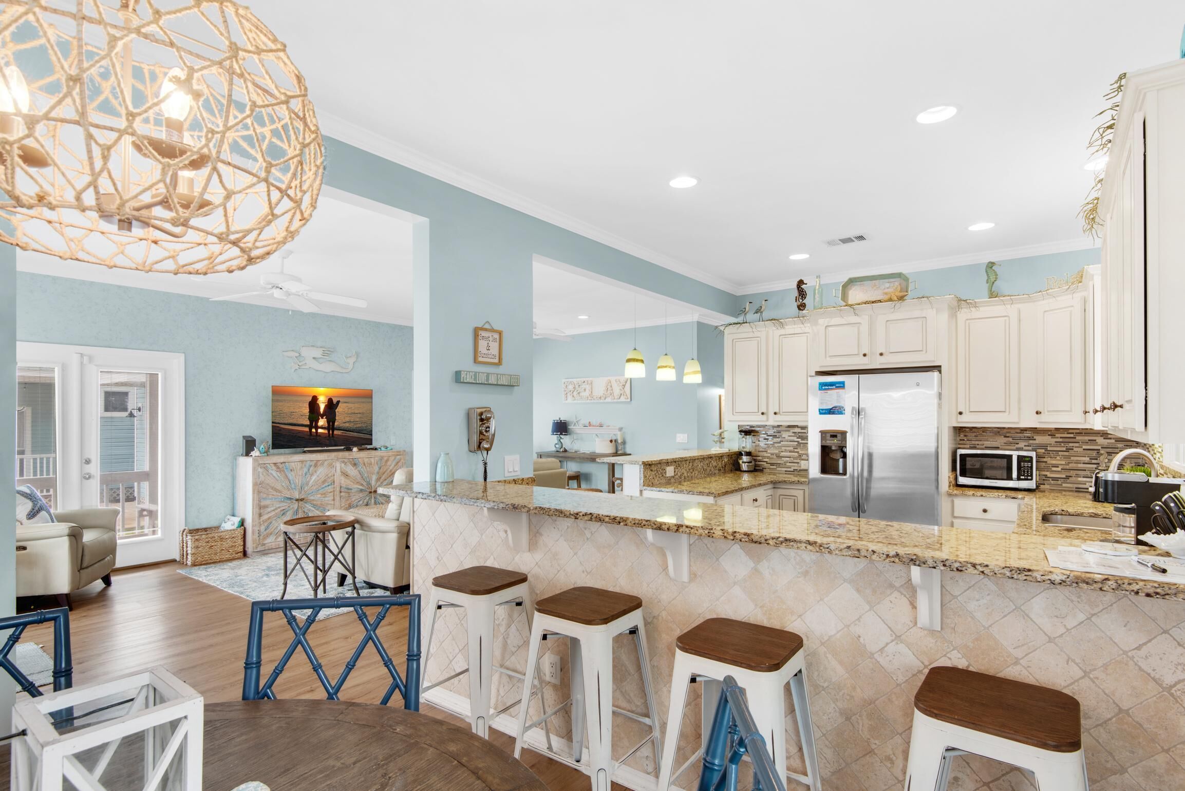 A modern kitchen with a central island, white cabinetry, and stainless steel appliances.