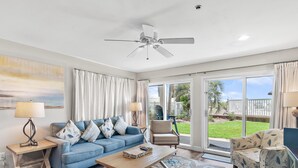 A living room with a blue sofa, a wooden coffee table, a beige armchair, and a ceiling fan.