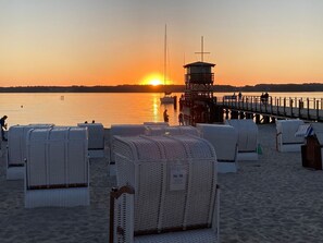 A beach with white wicker lounge chairs and a lifeguard tower. - Fewo1846 - Lille Loft - Fewo1846 - Lille Loft / Ebenerdiges Apartment mit 2 Schlafzimmern und Garten (Glücksburg (Ostsee))