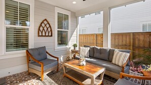 A sunlit patio with a wicker coffee table, a cushioned sofa, and a wooden chair. - Once Upon a Tide (Miramar Beach)