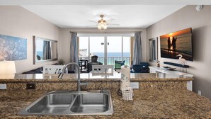A kitchen with granite countertops, a double sink, and a ceiling fan. - Ariel Dunes I 1905 (Miramar Beach)