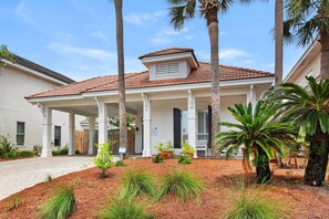 A two-story house with a covered porch, palm trees, and a well-maintained garden. - Catch of the Day (Destin)