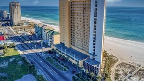 A high-rise hotel with multiple floors, a beach view, and a parking area.
