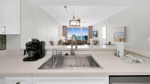 A modern kitchen with a built-in dishwasher, a coffee maker, and a large window overlooking a balcony.
