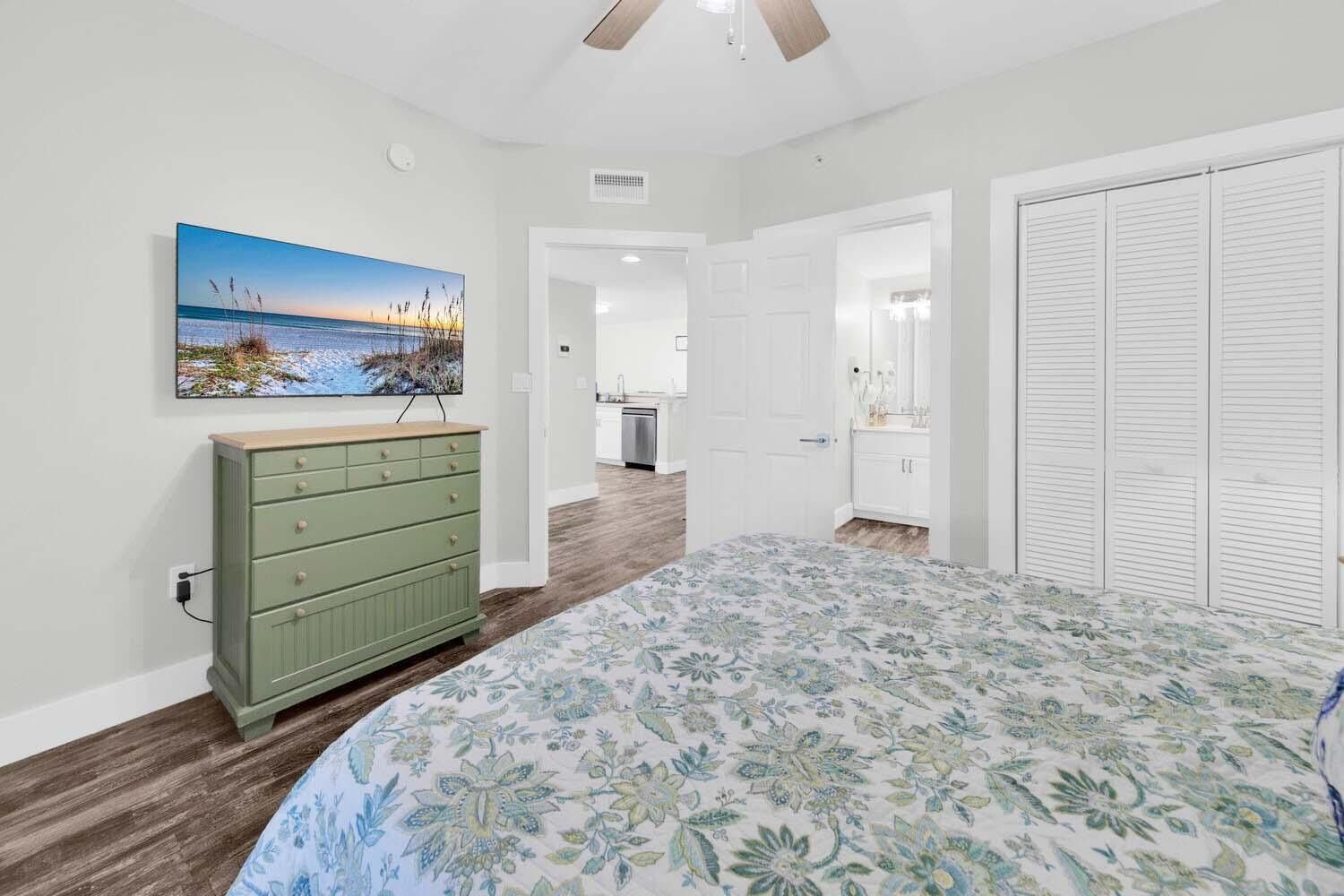A bedroom with a bed, dresser, and a painting of a beach scene.