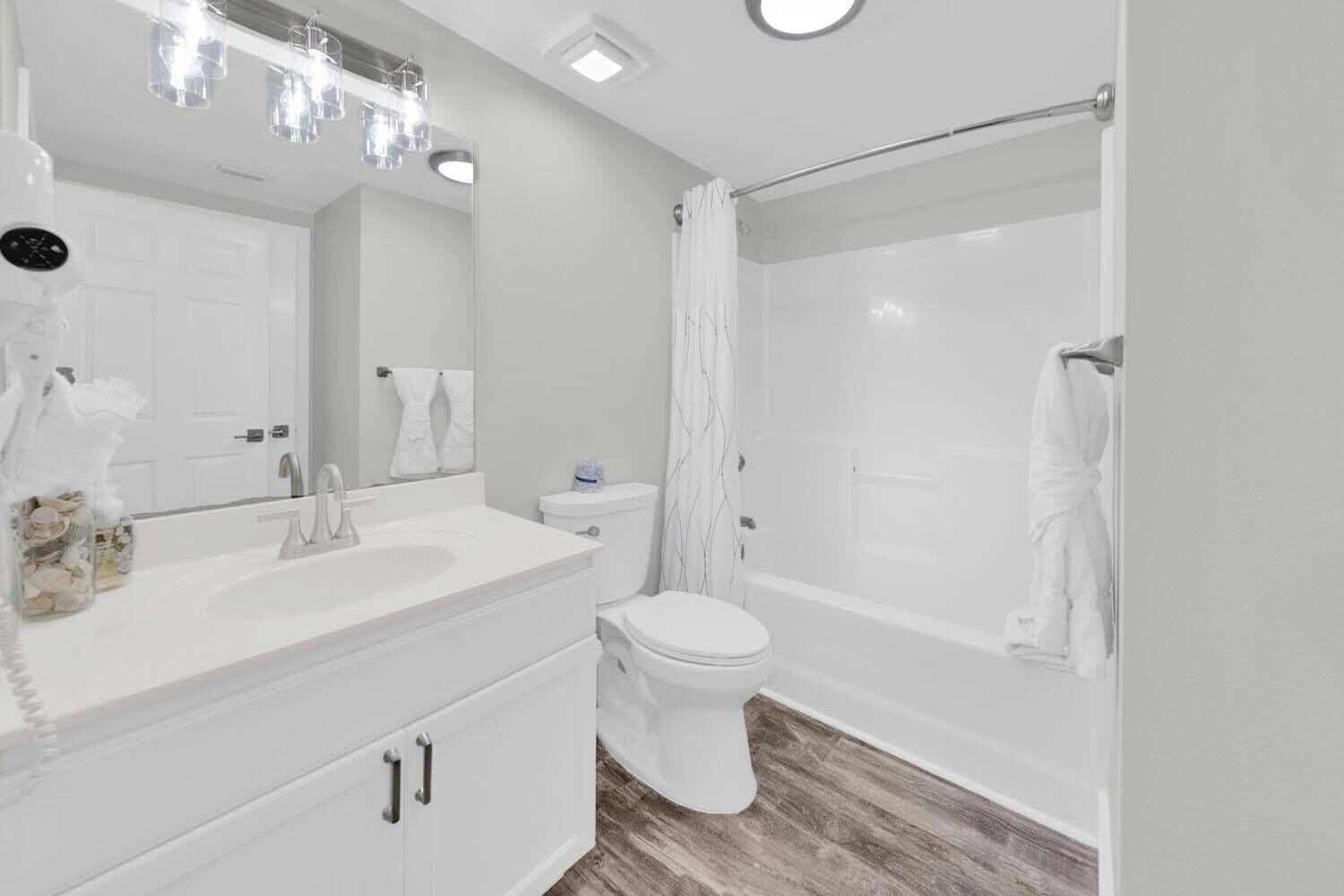 Une salle de bain moderne avec un meuble-lavabo blanc, des toilettes et une douche à l’italienne.