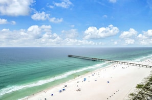 A beach with a pier extending into the ocean, sandy beach, and clear skies. - Sterling Reef 1904- Penthouse (Panama City Beach)
