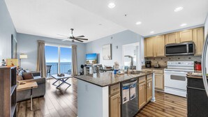 A modern kitchen with granite countertops, stainless steel appliances, and wooden cabinets. - Sterling Reef 1904- Penthouse (Panama City Beach)