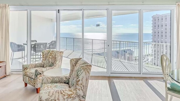 A spacious balcony with a view of the sea and buildings, furnished with a round table and two chairs. - Tides at Tops'l 907 (Miramar Beach)