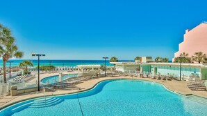 A resort pool area with a clear view of the ocean, lounge chairs, and umbrellas. - Tides at Tops'l 907 (Miramar Beach)