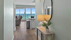 A room with a view of the ocean, a balcony with a chair, a lamp, and a potted plant. - Tides at Tops'l 907 (Miramar Beach)