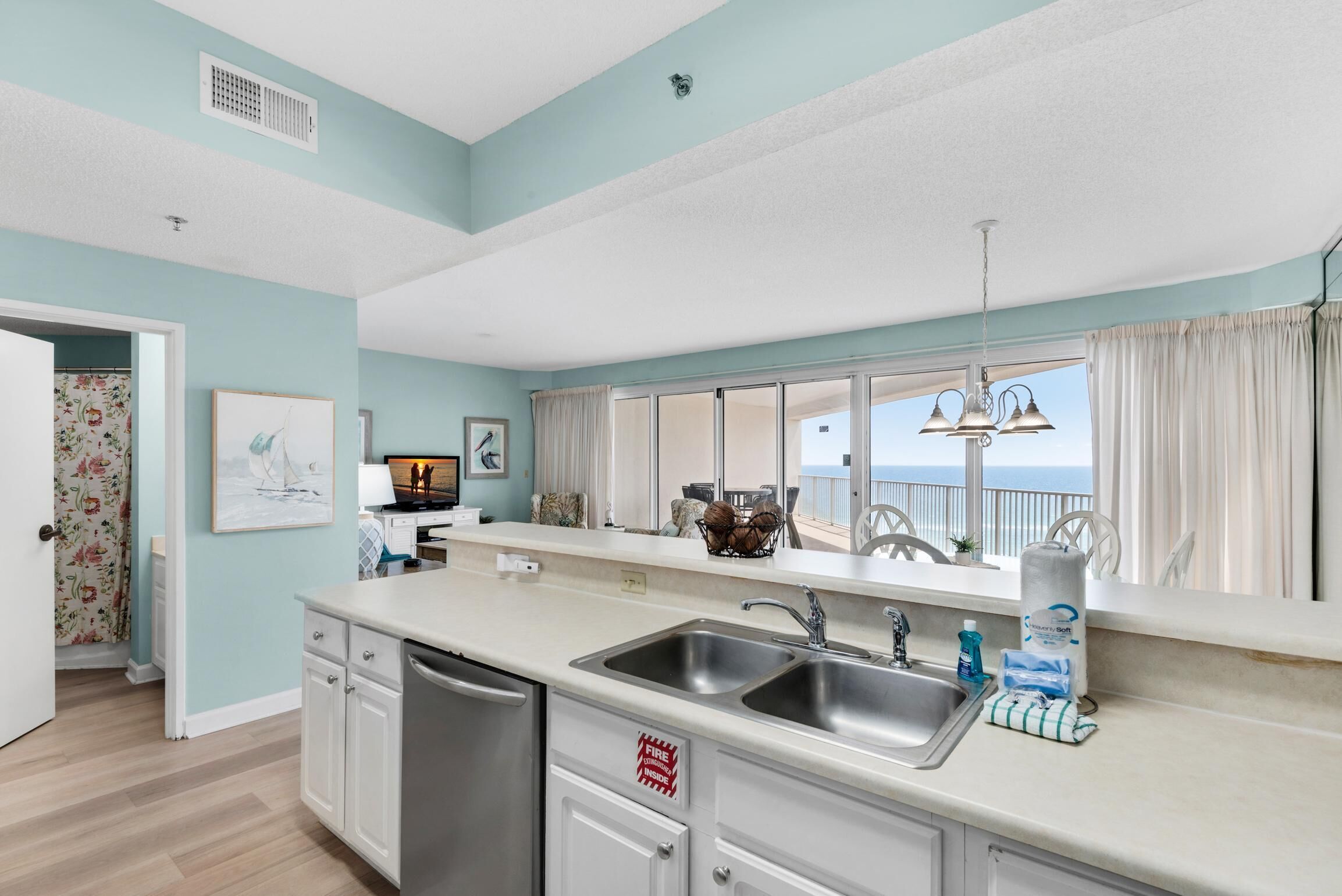 A kitchen with a large window, a sink, and a fire extinguisher sign.