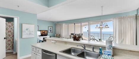 A kitchen with a large window, a sink, and a fire extinguisher sign.