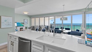 A spacious kitchen with a large island, white cabinetry, and a view of the ocean through large windows. - Tides at Tops'l 907 (Miramar Beach)