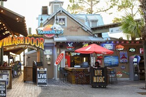 A bustling street scene with a variety of restaurants and bars, including Hammerhead's Bar & Grill and Village Door. - Luau I 7101 (Miramar Beach)
