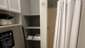 Un baño con inodoro, lavabo, cortina de ducha y estante con toallas.